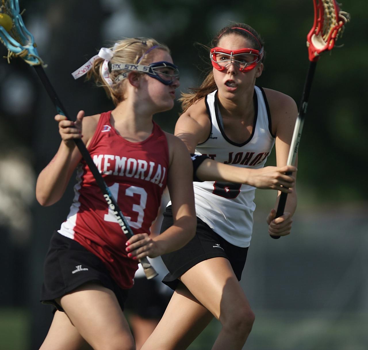services-03 Two female lacrosse players in action outdoors during a competitive game.