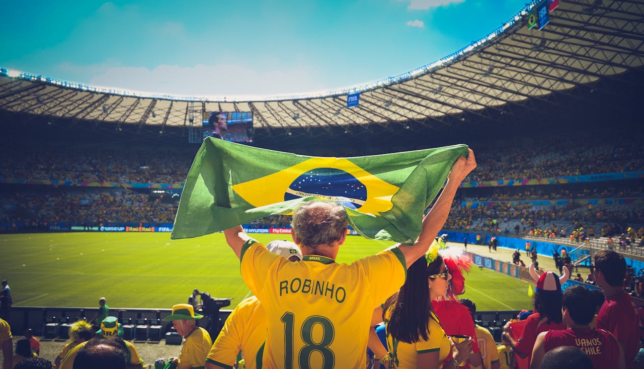 journey-02 Excited Brazilian fans holding flag at soccer match in vibrant stadium atmosphere.